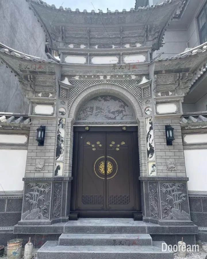 Dark-brown double door with gold cloud motifs and a gold ring medallion, in a carved stone gateway, installed at a client's home