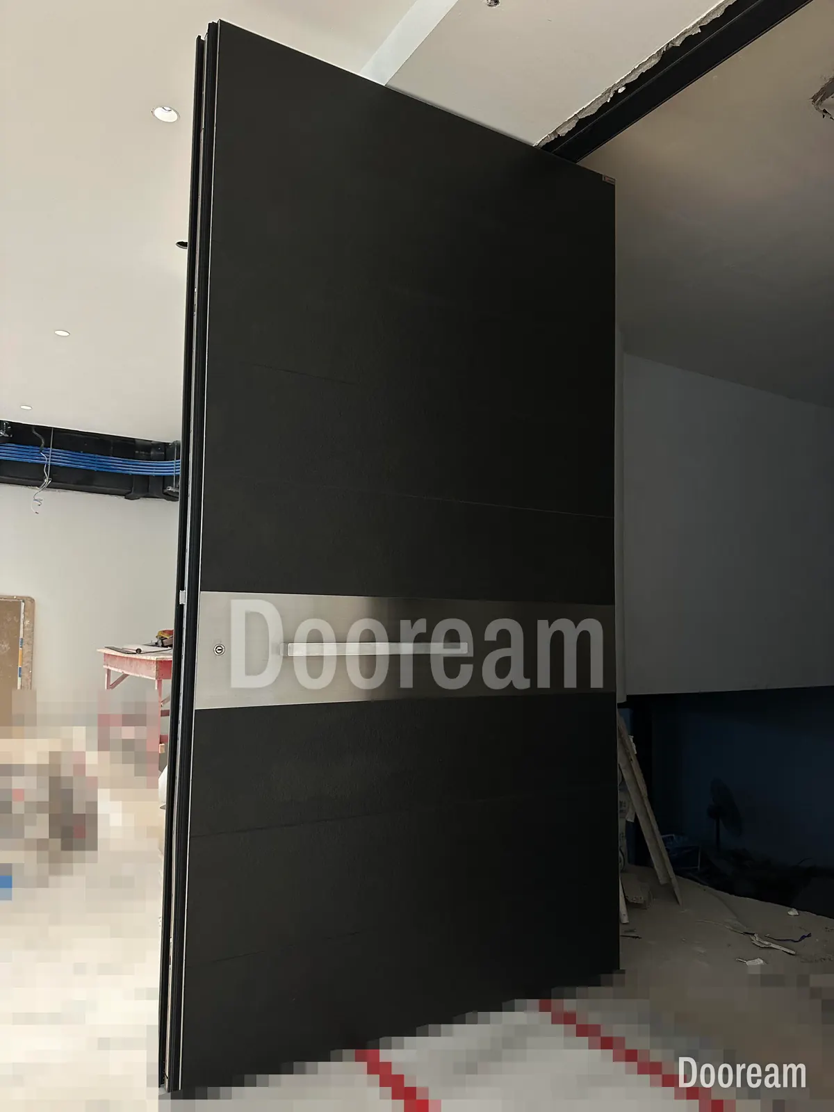 A black entrance door with a silver band, installed on site while the building is still under construction