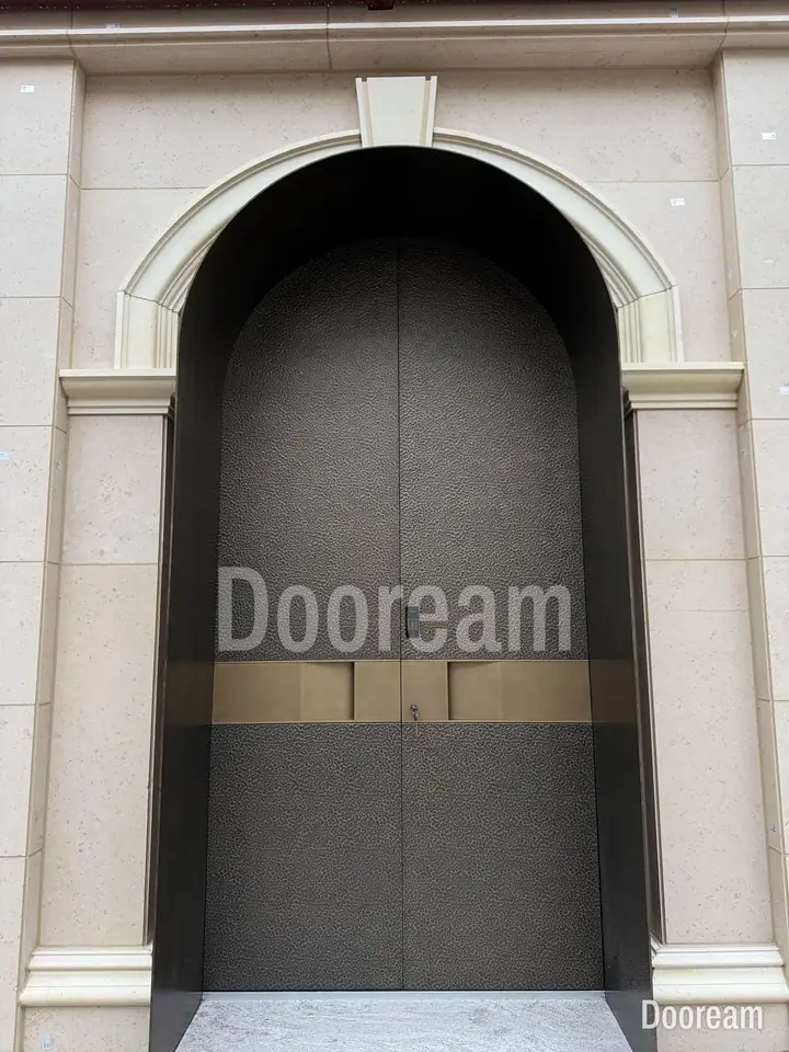 Grey hammered double door with a gold band, in an arched opening, installed