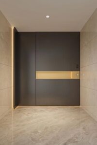 A modern asymmetrical mother-son armored entrance door in dark charcoal, featuring a horizontal luminous gold-niche with LED backlighting, integrated smart keypad, and subtle geometric relief.