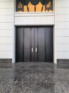 A massive four-panel armored entrance system with two central opening doors and two fixed sidelights, featuring a dark charcoal stone-like horizontal texture and vertical bronze decorative lines with smart lock integration.