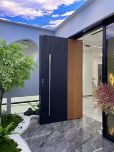 Flush-mount pivot door with asymmetrical bi-material design: matte black vertical ribbed texture on left, natural wood vertical grain on right, full-height slim stainless pull, seamlessly integrated into modern interior wall.