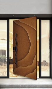 Flush-mount pivot door in natural walnut with 3D carved organic dune wave relief texture and full-height indigo blue abstract branch sculptural pull, seamlessly integrated into luxury interior wall under elegant ambient lighting.