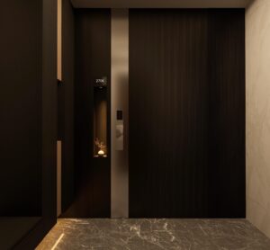 A tall, floor-to-ceiling black fluted pivot door with a vertical silver metallic center strip and a small, illuminated recessed niche containing a vase, set in a modern marble hallway.