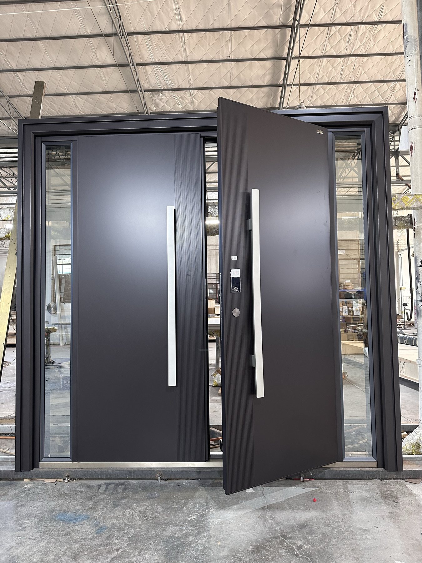 Black pivot entrance with side glass shown during factory production for UAE specification planning
